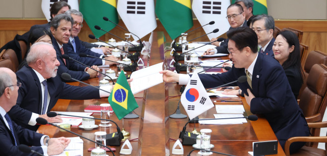 ▲이재명 대통령이 23일 청와대에서 열린 한-브라질 확대정상회담에서 룰라 브라질 대통령 요청으로 책에 사인한 뒤 전달하고 있다. (연합뉴스)