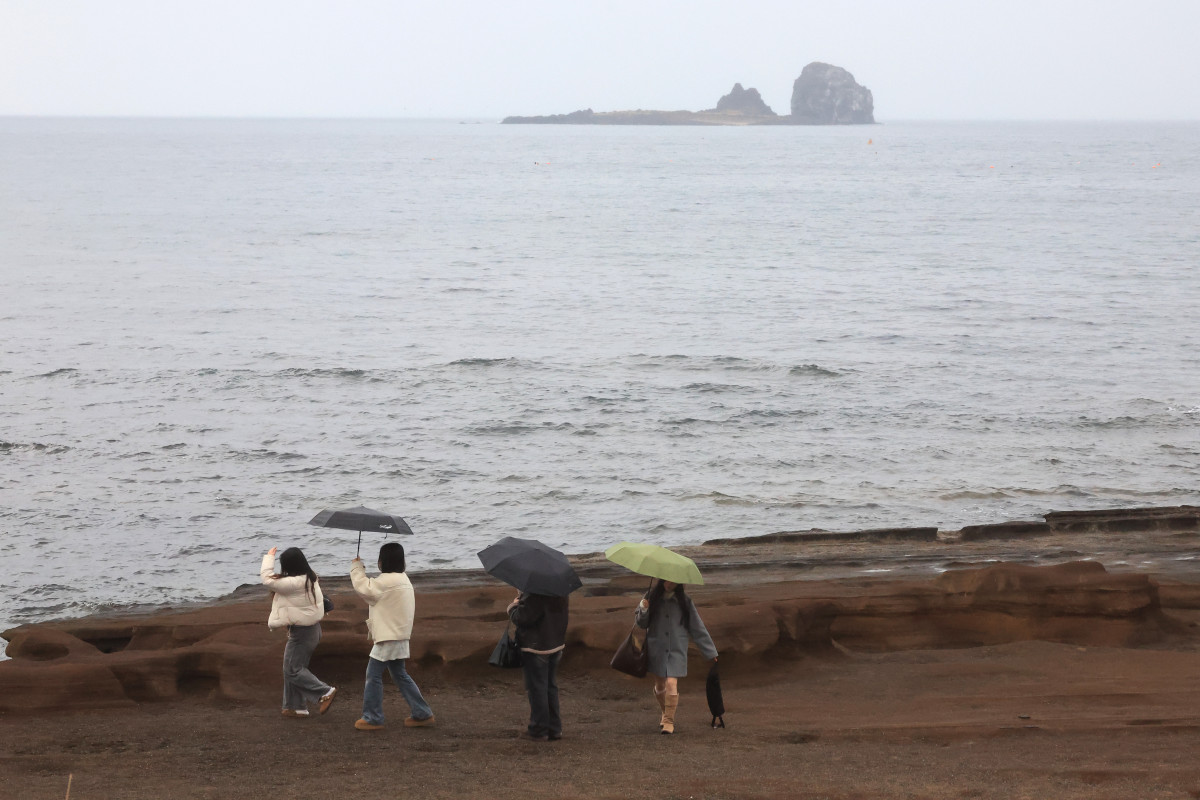 ▲10일 오전 제주 서귀포시 안덕면 사계리 해안을 찾은 관광객이 우산을 들고 바닷가 정취를 즐기고 있다. (연합뉴스)