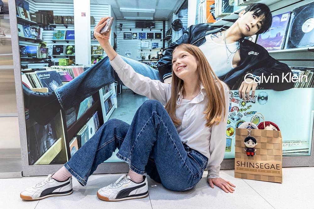 ▲신세계면세점 명동점 내 BTS 콘텐츠를 배경으로 셀카 찍는 외국인 모델 (사진제공=신세계면세점)