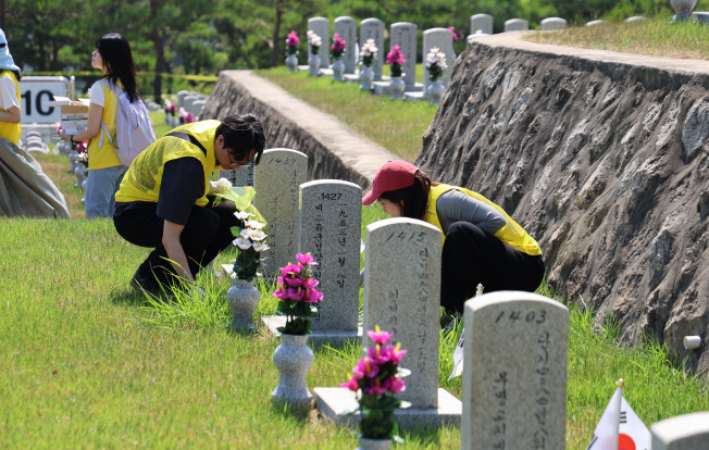 ▲2025년 6월, 오뚜기 봉사단이 국립서울현충원 장병묘역에서 비석 닦기 봉사활동에 참여하고 있다. (사진제공=오뚜기)