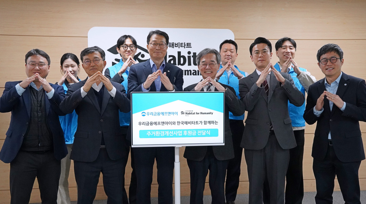 ▲(왼쪽에서 다섯번째부터) 우리금융에프엔아이 김건호 대표이사와 이광회 사무총장이 한국해비타트 본사에서 열린 후원금 전달식에서 양사 임직원과 함께 기념촬영을 하고 있다. (사진제공=우리금융)