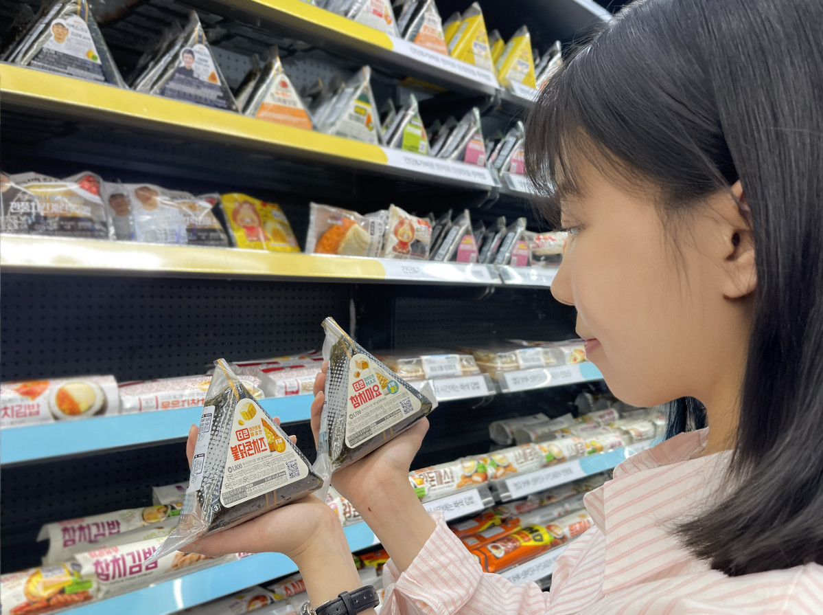 ▲GS25가 역대 최고 스펙으로 삼각김밥 '풀체인지 리뉴얼'을 추진하고 있다. 모델이 GS25가 '풀체인지 리뉴얼'을 완료한 '더큰 삼각김밥' 시리즈를 살펴보고 있다. (사진제공=GS리테일)