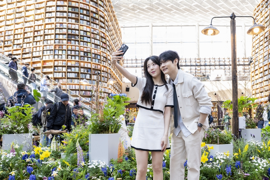 ▲스타필드 코엑스몰 별마당 도서관이 진행하는 ‘처음 돋는 첫잎처럼, 처음 여는 첫입처럼’ 특별전에서 모델들이 대형 서가를 배경으로 기념 사진을 남기고 있다. (사진제공=신세계프라퍼티)