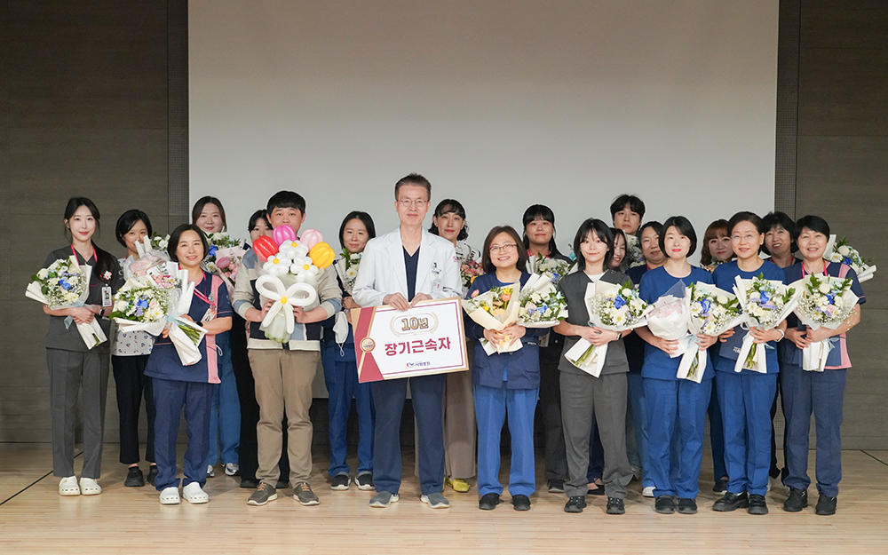 ▲시화병원이 개원 28주년 기념식에서 장기근속자 시상을 진행했다. 10년 장기근속 수상자들이 꽃다발을 들고 기념촬영하고 있다. (시화병원)