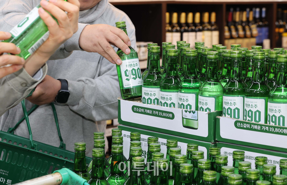 ▲6일 서울 송파구 가락몰 다농마트에서 시민들이 진열된 '착한소주 990'을 살펴보고 있다. 360ml 용량에 알코올 도수 16도인 '착한소주 990'은 조웅래 선양소주 회장이 직접 광고 모델로 참여해 마케팅 비용을 줄이고, 이를 가격 인하에 반영해 출시된 동네슈퍼 전용 상품이다. 소비자 가격은 병당 990원, 한 박스(20병) 기준 1만 9800원이다.