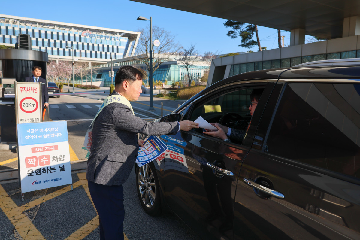 ▲한국서부발전은 8일 충남 태안 본사에서 임직원과 협력사를 대상으로 ‘에너지 절약 국민행동’ 안내문을 배부하고 차량 2부제 참여를 독려했다. 사진은 이정복 서부발전 사장이 직원에게 안내문을 전달하는 모습. (사진제공=한국서부발전)