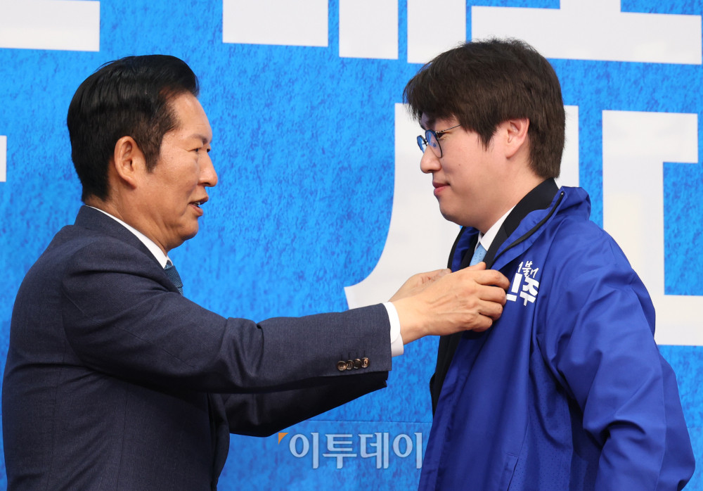 ▲하정우(오른쪽) 전 청와대 AI수석이 29일 서울 여의도 국회에서 열린 민주당 인재영입식에서 정청래 당대표에게 파란 점퍼를 받고 있다. 고이란 기자 photoeran@