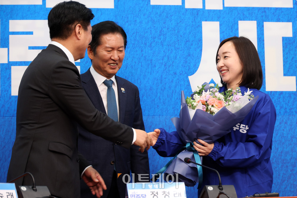 ▲전은수(오른쪽) 전 청와대 대변인이 29일 서울 여의도 국회에서 열린 민주당 인재영입식에서 조승래 사무총장에게 꽃다발을 받고 있다. 가운데는 정청래 당대표. 고이란 기자 photoeran@