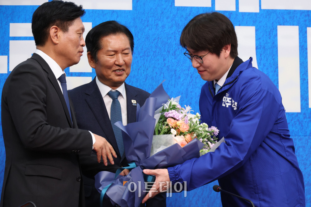 ▲하정우(오른쪽) 전 청와대 AI수석이 29일 서울 여의도 국회에서 열린 민주당 인재영입식에서 조승래 사무총장에게 꽃다발을 받고 있다. 가운데는 정청래 당대표. 고이란 기자 photoeran@