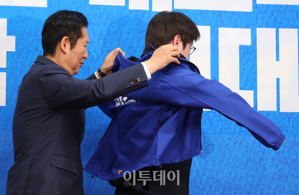▲하정우(오른쪽) 전 청와대 AI수석이 29일 서울 여의도 국회에서 열린 민주당 인재영입식에서 정청래 당대표에게 파란 점퍼를 받고 있다. 고이란 기자 photoeran@