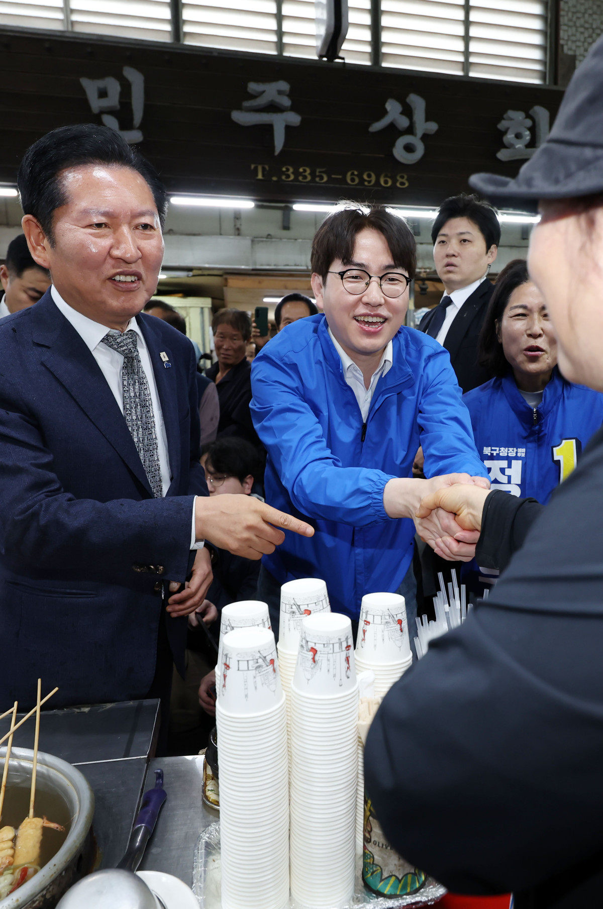 ▲정청래 더불어민주당 대표가 3일 부산 북구 구포시장에서 하정우 전 청와대 AI미래기획수석 등과 상인들에게 인사하며 지지를 호소하고 있다.