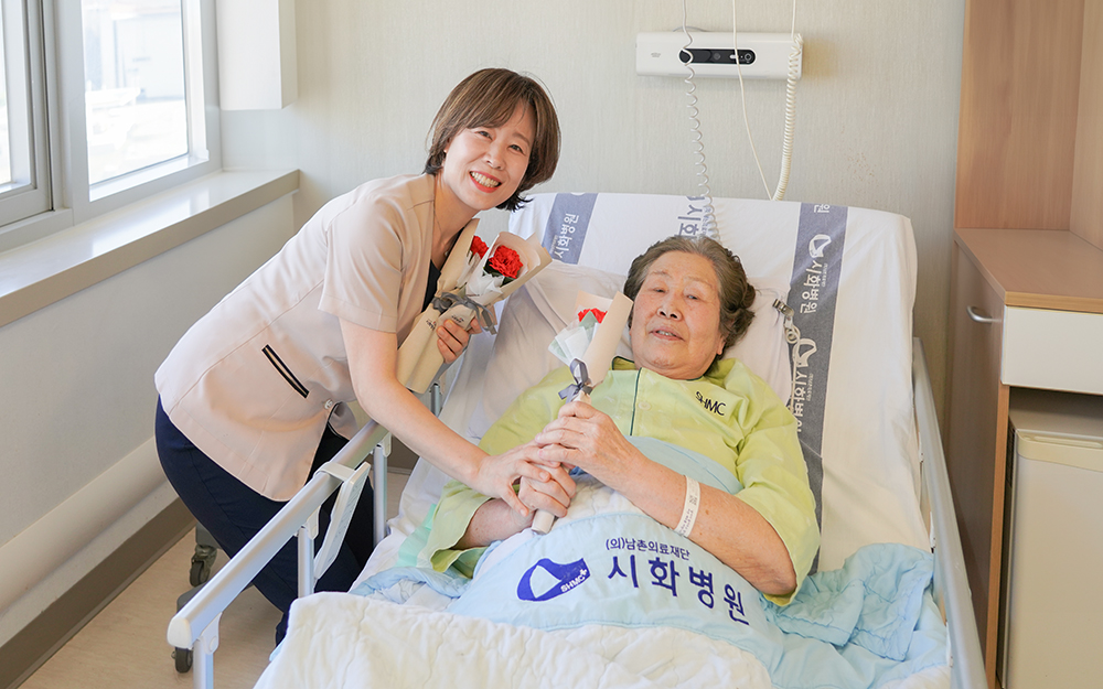 ▲시화병원 의료진이 8일 어버이날을 맞아 65세 이상 입원 환자에게 비누꽃 카네이션을 전달하고 있다. 환자가 카네이션을 받아 들고 환하게 웃고 있다. (시화병원)