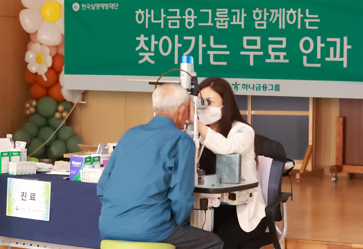▲검진에 참석한 어르신이 세극등현미경을 통해 안구 정밀 검진을 받고 있다. (하나금융)