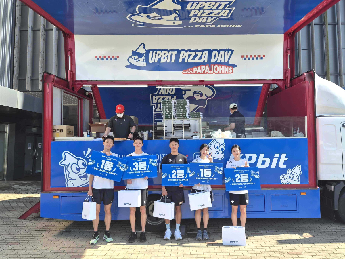 ▲22일 충북 진천 국가대표선수촌에서 열린 2026 팀코리아 트레일러닝(Trail Running) 훈련에 참가한 선수들이 업비트 피자데이 이벤트 트럭 앞에서 포즈를 취하고 있다. (사진=두나무)