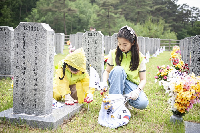 ▲전북은행 목련회 회원과 자녀들이 국립임실호국원 묘역에 태극기를 꽂고 주변 환경을 정비하고 있다. (사진제공=전북은행)