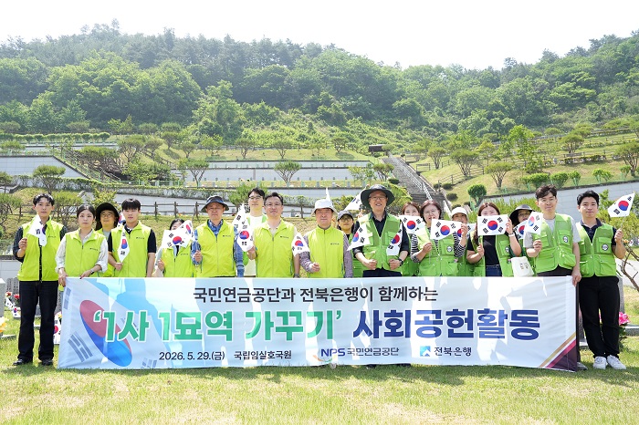▲전북은행과 국민연금공단 직원들이 지난 29일 국립임실호국원에서 ‘1사 1묘역 가꾸기’ 공동 사회공헌활동을 마친 뒤 태극기를 들고 기념촬영을 하고 있다. (사진제공=전북은행)