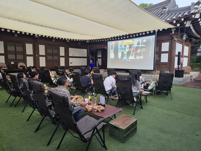 ▲관람객들이 전주한옥마을 트래디라운지에서 열린 ‘전주 심야극장’에 참여해 한옥의 정취 속에서 영화를 관람하고 있다. (사진제공=전주시)