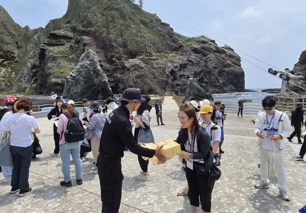 ▲독도 입도 후 독도지킴이학교 지도교사인 천수주초등학교 정수경 교사가 독도 경비대에게 학생들의 응원 편지를 전달하고 있다. (동북아역사재단)