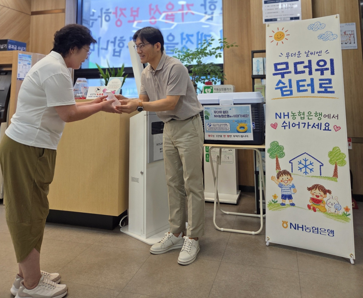 ▲NH농협은행 수원시지부 직원이 15일 영업점 무더위 쉼터를 찾은 시민에게 생수와 부채를 전달하고 있다. (경기농협)