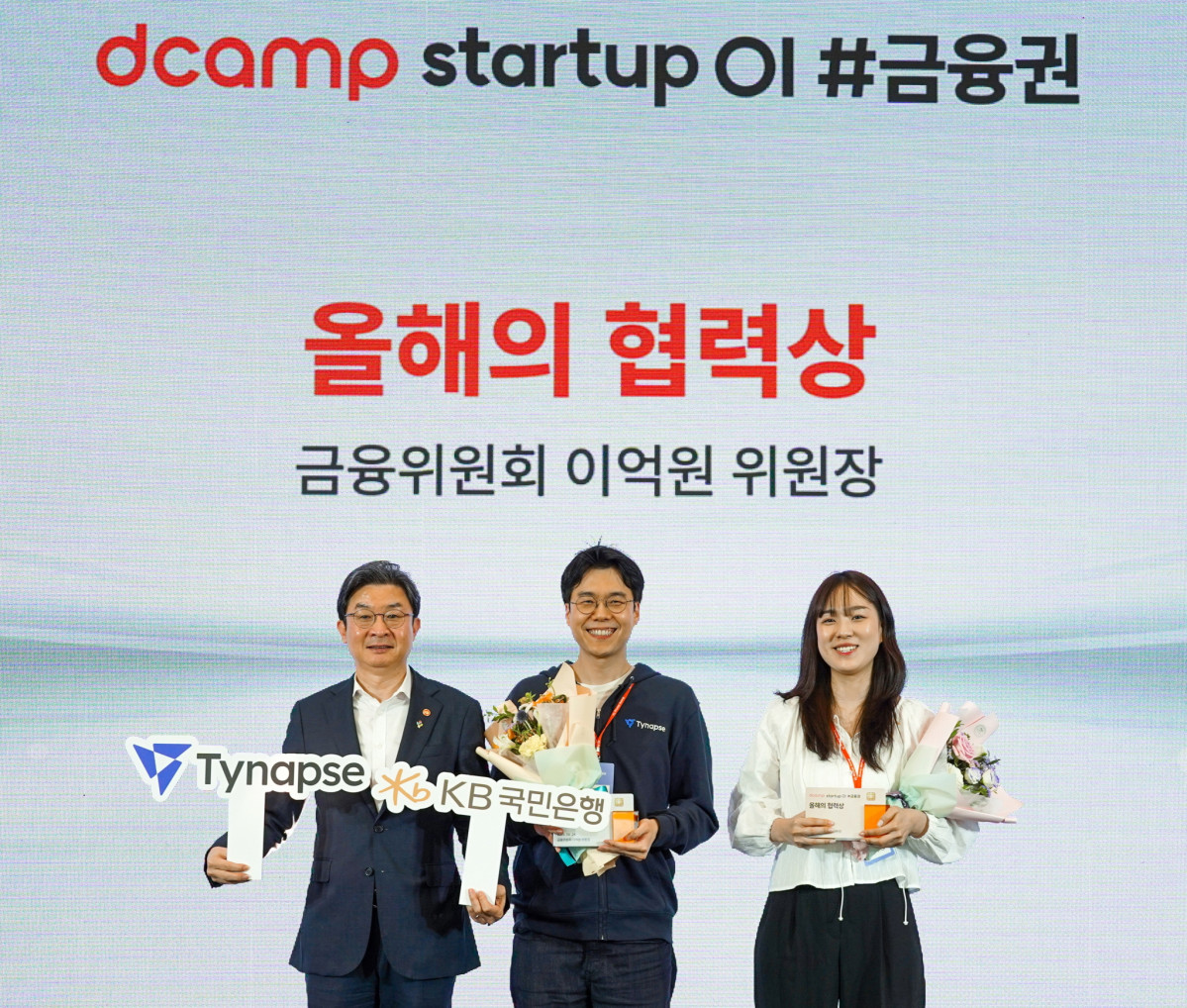 ▲(왼쪽부터) 이억원 금융위원장, 티냅스 강민승 대표, KB국민은행 관계자가 24일 서울 마포구에서 진행된 '스타트업 오픈이노베이션' 행사에서 기념촬영을 하고 있다. (사진제공=KB금융)
