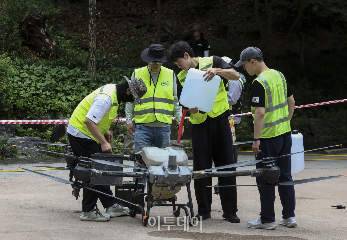 ▲25일 오전 서울 노원구 불암산 일대에서 서울시 관계자 등이 붉은등우단털파리(러브버그) 살수드론 방제작업 시연을 위해 물을 주입하고 있다. 서울시는 비와 바람에 취약한 러브버그의 특성을 고려해 살수드론을 이용해 발생지역 상공에서 물을 분사해 비행 능력을 떨어뜨리고, 활동과 확산을 일시적으로 억제한다. 살수드론 방제작업은 접근이 어려운 산림 및 경사지에 대한 광범위한 방제를 목적으로 진행된다. 고성준 기자 joonko1@