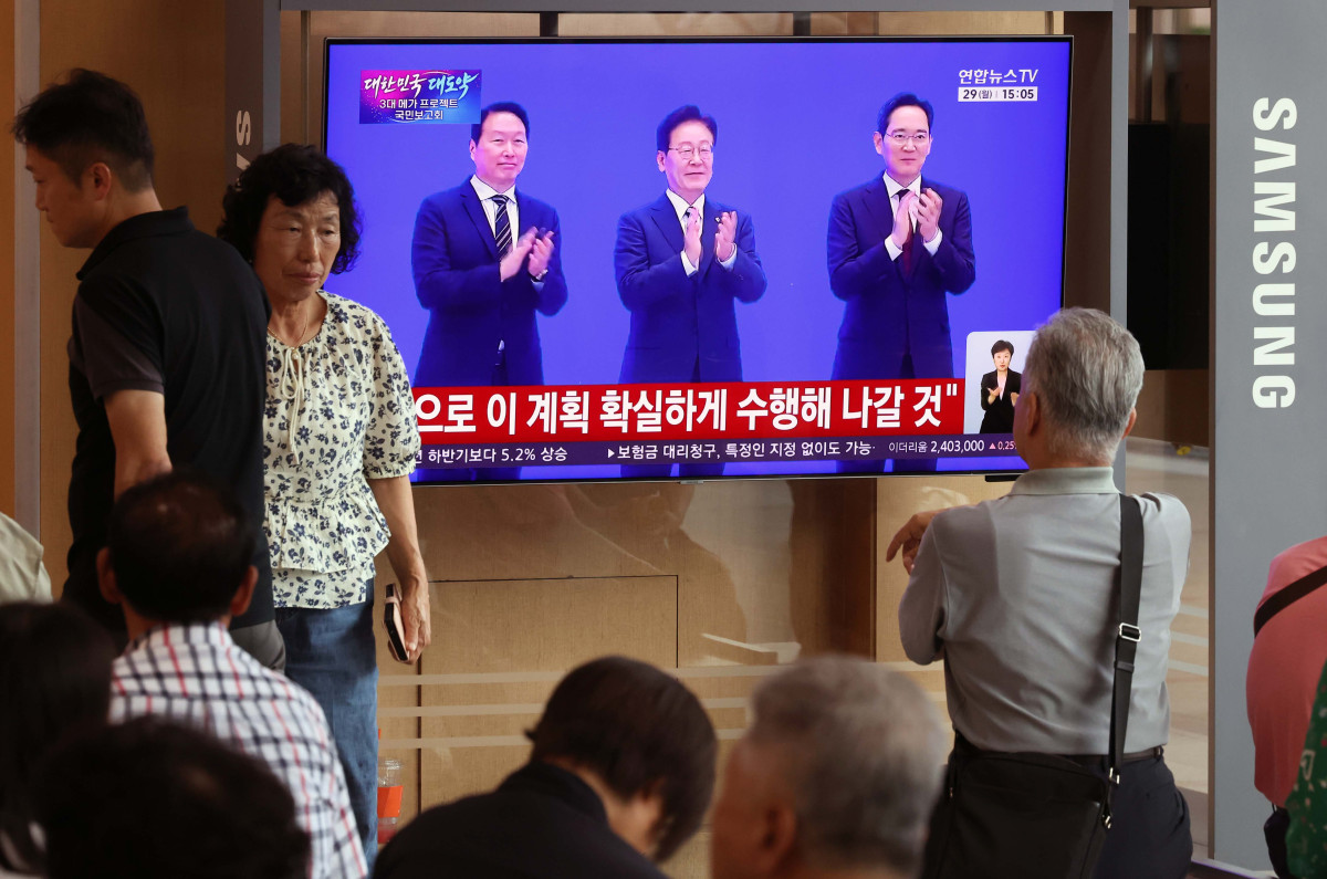 ▲이재명 대통령이 29일 '대한민국 대도약 3대 메가 프로젝트 국민보고회'를 주재하며 반도체, 피지컬AI, 인공지능(AI) 데이터센터를 핵심 축으로 한 대규모 국가 투자 계획을 발표한 뒤 이재용 삼성전자 회장, 최태원 SK그룹 회장과 인사하는 모습이 서울역 대합실 텔레비전을 통해 생중계되고 있다. 신태현 기자 holjjak@
