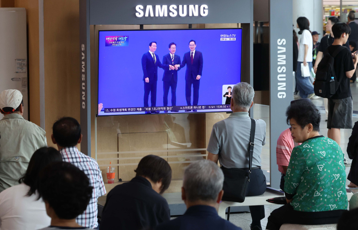 ▲이재명 대통령이 29일 '대한민국 대도약 3대 메가 프로젝트 국민보고회'를 주재하며 반도체, 피지컬AI, 인공지능(AI) 데이터센터를 핵심 축으로 한 대규모 국가 투자 계획을 발표한 뒤 이재용 삼성전자 회장, 최태원 SK그룹 회장과 인사하는 모습이 서울역 대합실 텔레비전을 통해 생중계되고 있다. 신태현 기자 holjjak@