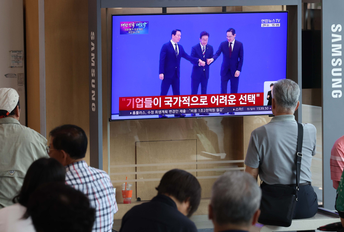 ▲이재명 대통령이 29일 '대한민국 대도약 3대 메가 프로젝트 국민보고회'를 주재하며 반도체, 피지컬AI, 인공지능(AI) 데이터센터를 핵심 축으로 한 대규모 국가 투자 계획을 발표한 뒤 이재용 삼성전자 회장, 최태원 SK그룹 회장과 인사하는 모습이 서울역 대합실 텔레비전을 통해 생중계되고 있다. 신태현 기자 holjjak@