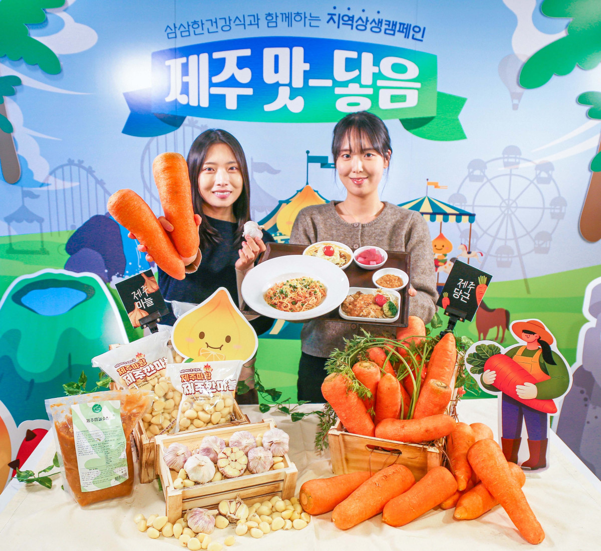 ▲현대그린푸드 직원들이 제주산 당근과 남도종 마늘을 활용해 만든 이색 급식 메뉴인 '당근명란오일파스타'와 '마늘소스 허브닭구이'를 소개하고 있는 모습. (사진제공=현대그린푸드)