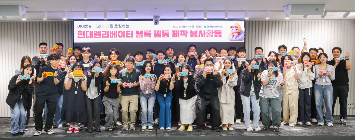 ▲지난달 23일 현대엘리베이터 임직원들이 충주 스마트캠퍼스 대강당에서 열린 '블록필통 만들기' 봉사활동에 참여해 기념 촬영을 하고 있다. (사진제공=현대엘리베이터)