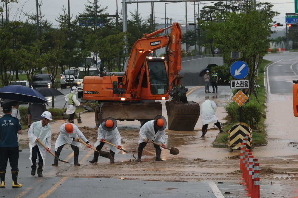 ▲폭우가 내린 9일 세종시 한별동 BRT 교차로 부근 도로가 공사장에서 흘러내린 토사에 덮여 침수되자 작업자들이 복구작업을 벌이고 있다. (연합뉴스)