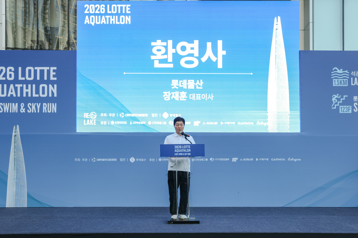 ▲장재훈 롯데물산 대표이사가 12일 서울 송파구 롯데월드타워 앞에서 열린 2026 롯데 아쿠아슬론 개회식 무대에 올라 환영사를 하고 있다. (사진제공=롯데물산)
