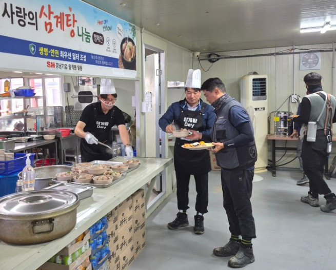 ▲이기동 경남기업 대표(맨 왼쪽)와 성유진 건축사업실장(왼쪽 두 번째)이 16일 경기 양주시 양주 옥정 A-22블록(BL) 아파트 건설 1공구 현장에서 혹서기 온열질환 예방 캠페인의 일환으로 진행된 ‘삼계탕 Day’에 배식자로 나서 근로자들에 삼계탕을 나눠주고 있다. (사진제공=SM그룹)