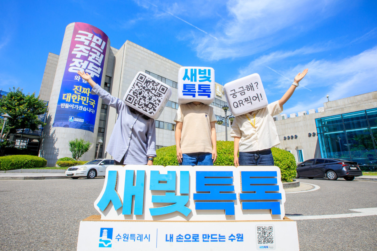 ▲수원시 관계자들이 수원시청 청사 앞에서 새빛톡톡을 홍보하는 사진을 찍고 있다. (수원시)