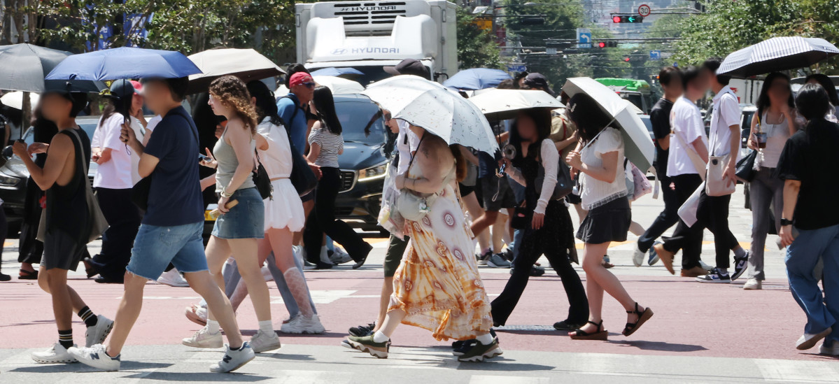 ▲서울 성수동 거리에서 시민 및 외국인들이 양산을 쓰고 이동하고 있다. (연합뉴스)