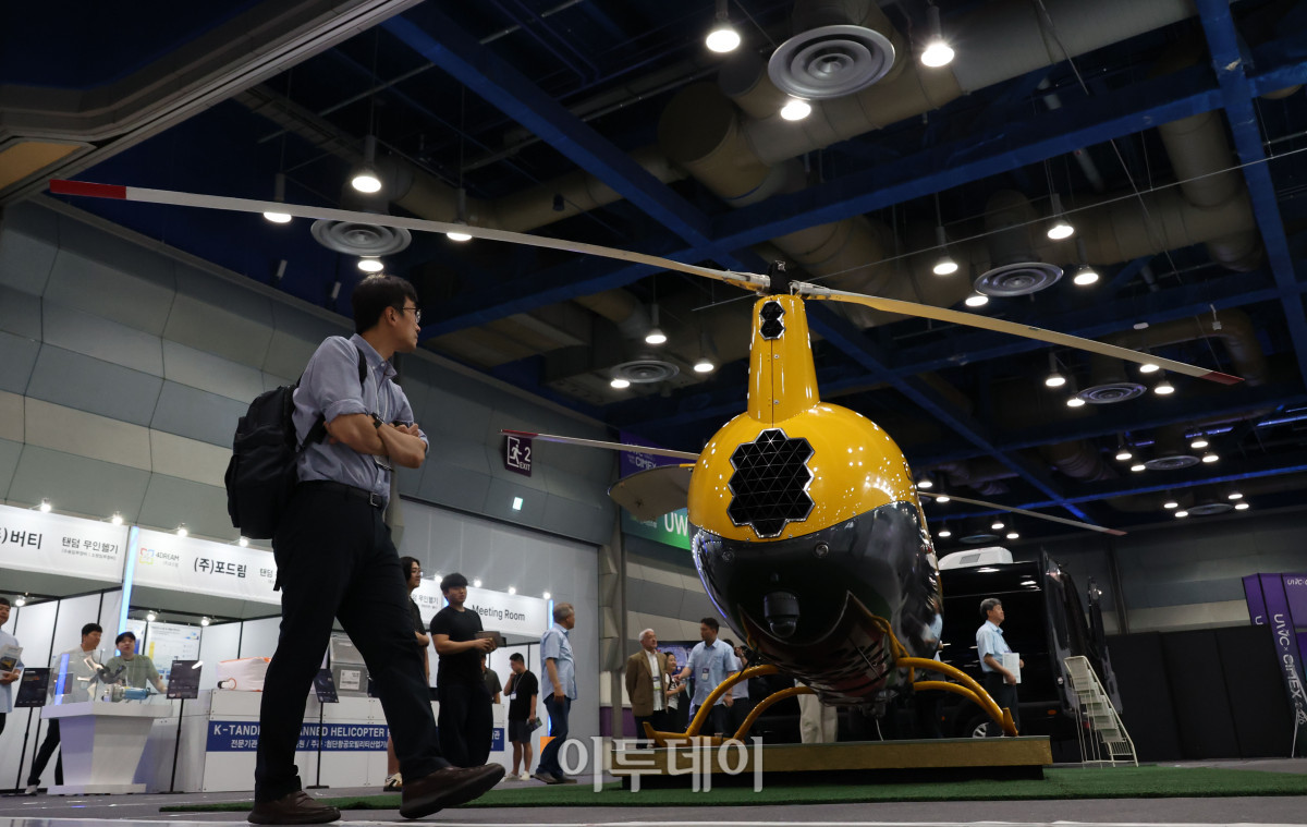 ▲25일 서울 강남구 삼성동 코엑스에서 열린 2026 퓨처모빌리티위크에서 관람객이 월드콥터(WORLDCOPTER)의 자동차 엔진을 탑재한 로봇헬기 카코맥스(CARGO-MAX)를 살펴보고 있다. 이번 행사는 EV트렌드코리아 2026, 2026 자율주행모빌리티산업전(AME 2026), 무인이동체X민군협력엑스포가 27일까지 동시에 열리며 완성차와 배터리, 충전 인프라부터 인공지능(AI), 소프트웨어 정의 차량(SDV), 로보택시까지 미래 모빌리티 생태계 전반의 혁신 기술을 한자리에서 선보인다. 고이란 기자 photoeran@