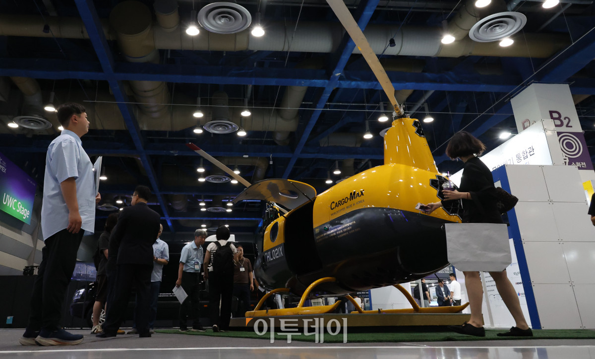 ▲25일 서울 강남구 삼성동 코엑스에서 열린 2026 퓨처모빌리티위크에서 관람객이 월드콥터(WORLDCOPTER)의 자동차 엔진을 탑재한 로봇헬기 카코맥스(CARGO-MAX)를 살펴보고 있다. 이번 행사는 EV트렌드코리아 2026, 2026 자율주행모빌리티산업전(AME 2026), 무인이동체X민군협력엑스포가 27일까지 동시에 열리며 완성차와 배터리, 충전 인프라부터 인공지능(AI), 소프트웨어 정의 차량(SDV), 로보택시까지 미래 모빌리티 생태계 전반의 혁신 기술을 한자리에서 선보인다. 고이란 기자 photoeran@
