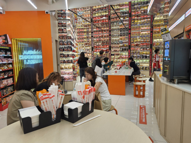 ▲26일 오후 이마트24 K푸드랩 명동점 2층에서 외국인 관광객들이 '라면 아카이브월'을 구경, 라면을 시식하고 있다. (사진=정영인 기자 oin@)