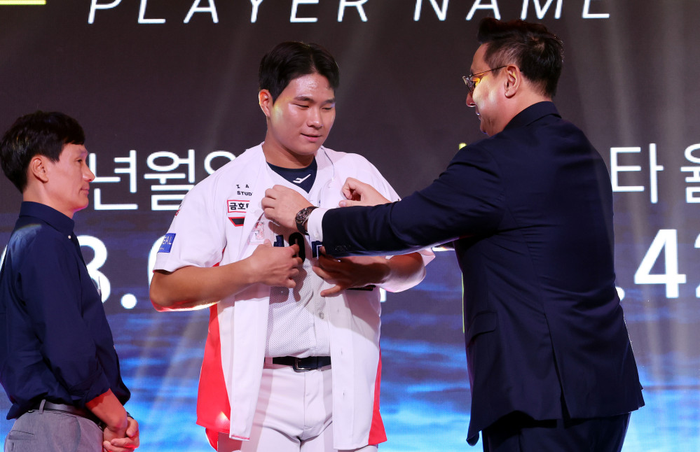 ▲21일 오후 서울 송파구 롯데호텔 월드 크리스탈볼룸에서 열린 2027 KBO 신인 드래프트, KIA 심재학 단장이 전체 3순위로 경남고 이호민를 지명한 후 유니폼을 입혀주고 있다. (뉴시스)