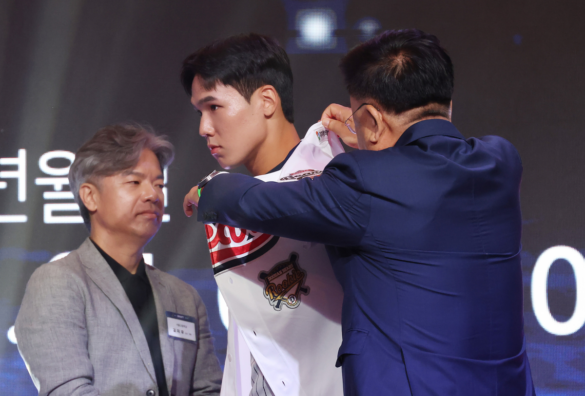 ▲지난달 21일 서울 롯데호텔 월드에서 열린 2027 KBO 신인 드래프트. 1라운드 2순위로 두산 베어스 지명을 받은 서울고 김지우가 유니폼을 받아 입고 있다. (연합뉴스)