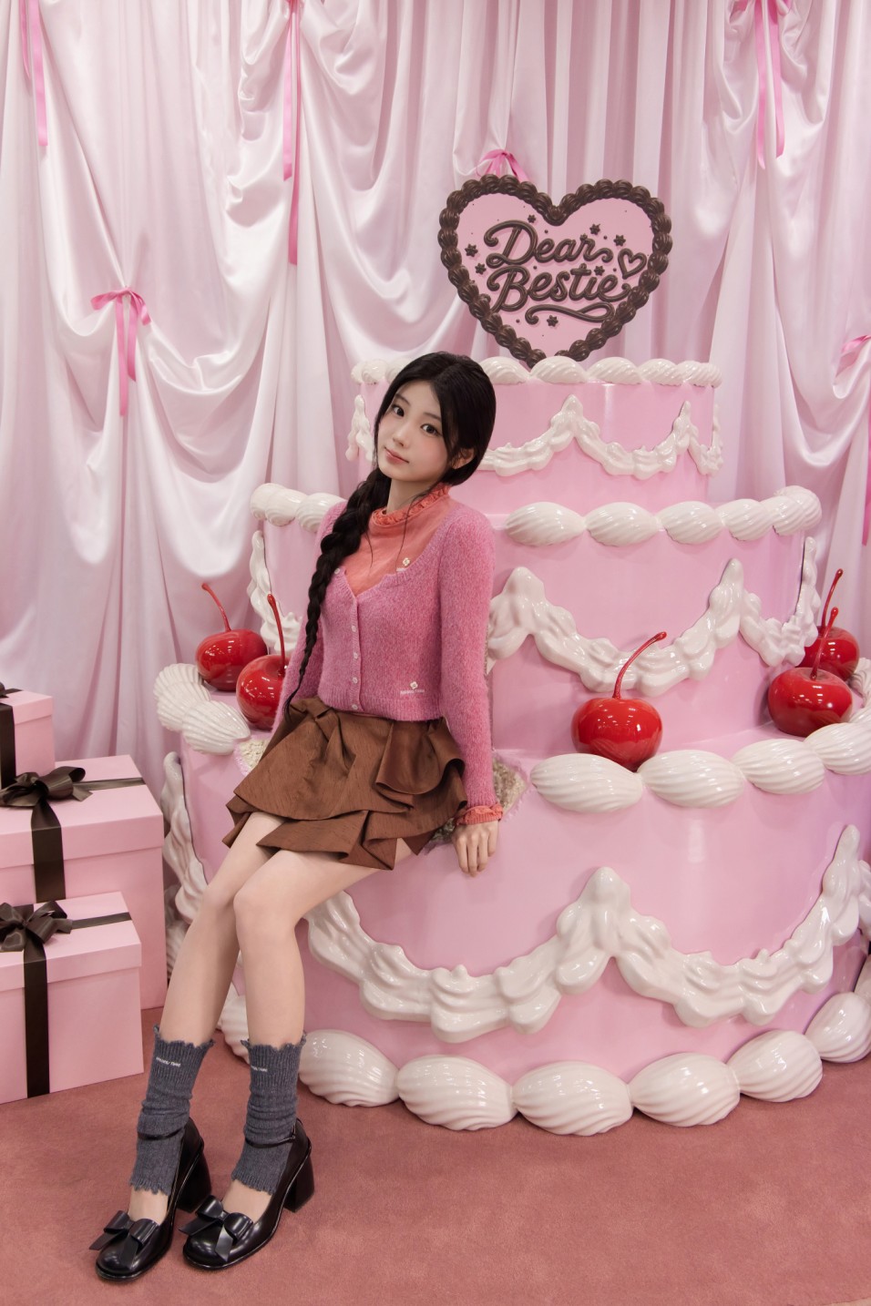 ▲그룹 아일릿의 원희가 10일 서울 성수동 롬앤 핑크오피스에서 열린 10주년 기념 팝업스토어 프리오픈 행사장에 마련된 핑크색 케이크 모양 배경 앞에 앉아 있다. (사진제공=아이패밀리에스씨)