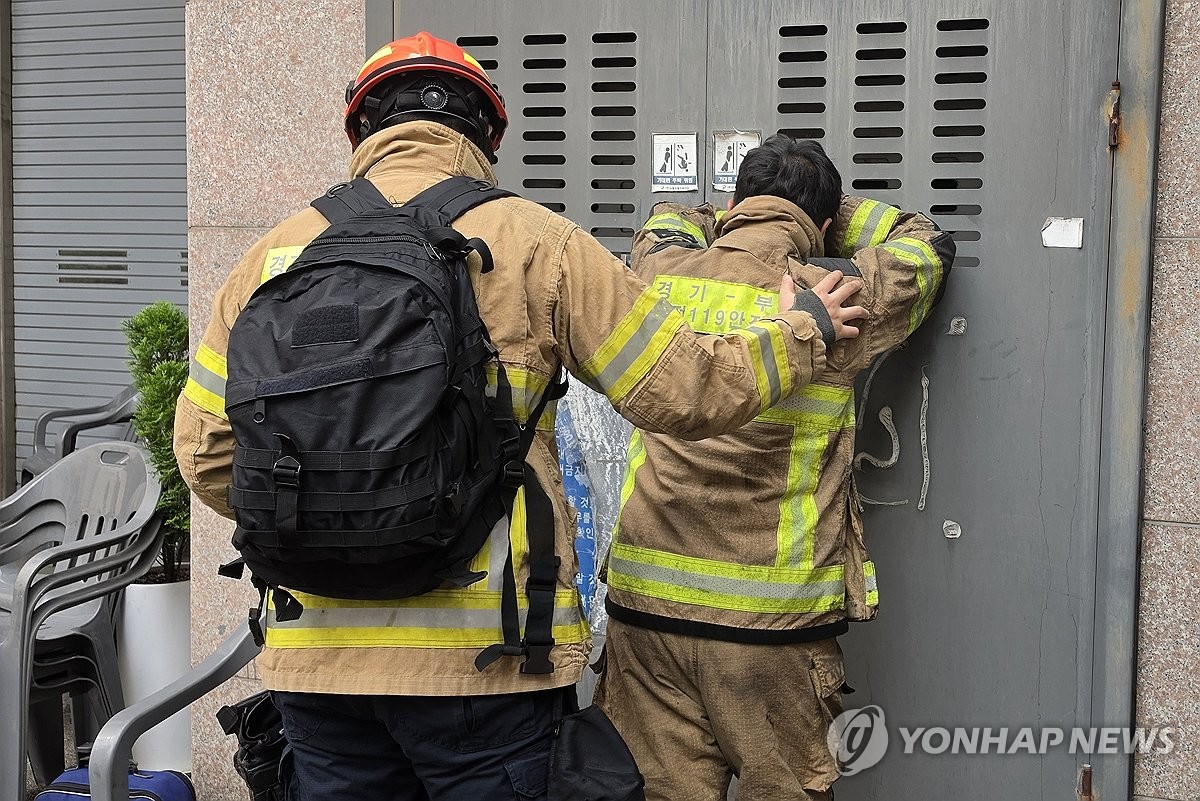 ▲16일 경기 부천시 오정구 도장공장 화재 진압을 마친 소방대원이 동료 소방관의 중상 소식에 건물 벽을 짚고 고개를 숙이자 다른 대원이 등을 감싸고 있다. (연합뉴스)
