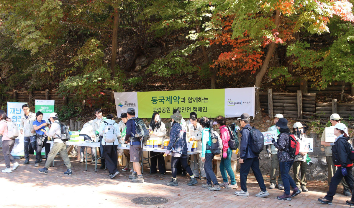 ▲17일 서울 도봉산 등산로 입구에서 동국제약 임직원들이 산행 안전수칙과 구급함 위치가 표시된 지도를 탐방객들에게 배포하고 있다. (사진제공=동국제약)