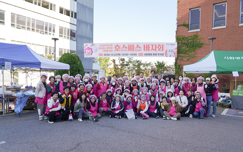 ▲한마음 호스피스 자원봉사자와 시화병원 임직원들이 22일 경기 시흥시 시화병원 후문 주차장에서 열린 ‘2026 제16회 호스피스 바자회'를 마친 뒤 기념촬영을 하고 있다. 이날 바자회 수익금은 전액 지역 내 의료 취약계층 환우의 치료비와 호스피스 완화의료 돌봄사업에 쓰인다. (시화병원)